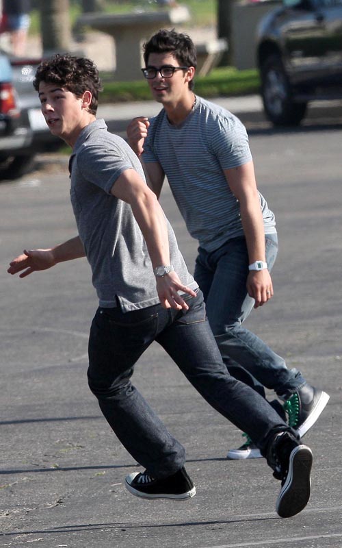 The Jonas Brothers Tossing A Football On Set